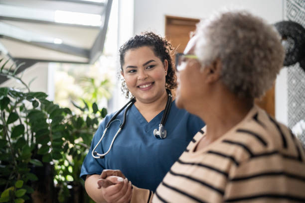 home caregiver helping senior woman walking at home